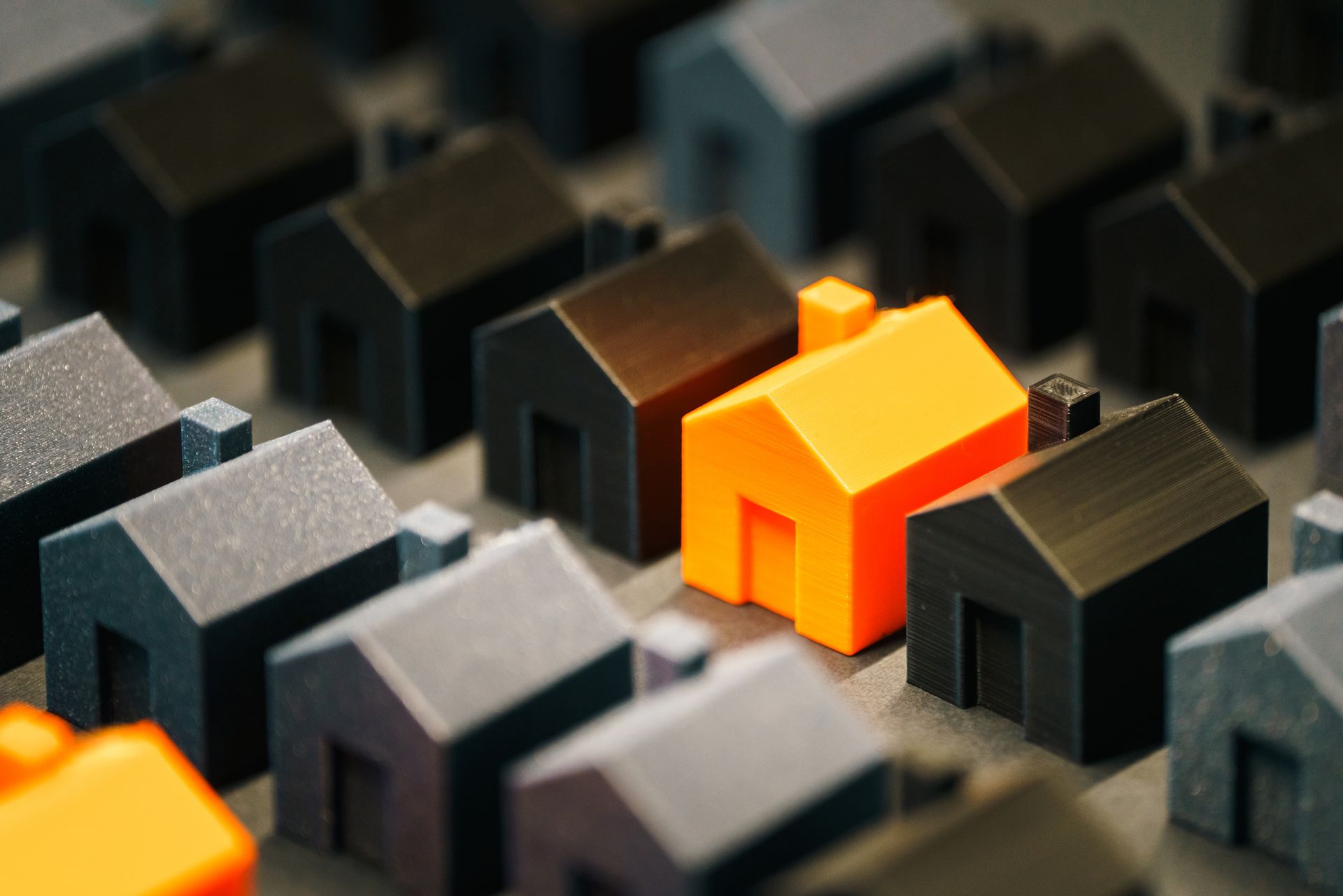 A row of model houses on documents with one yellow house standing out.